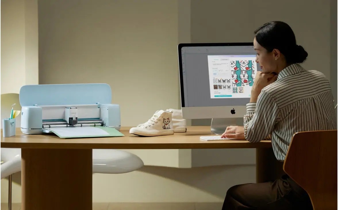 Woman sitting at a desk and computer in a slightly dim room. The computer screen showss LOKLiK IdeaStudio. There is also a LOKLiK iCraft™ in Bubble Blue on the table.