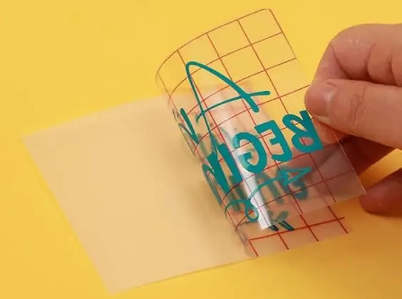 Close-up of a piece of grid transfer tape pulling a design from the PET backing.