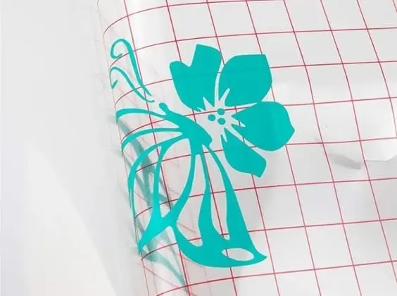 Close-up of a piece of grid transfer tape pulling a design from the PET backing.