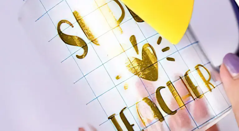 Grid transfer tape with a transferred design being placed on a glass mug.